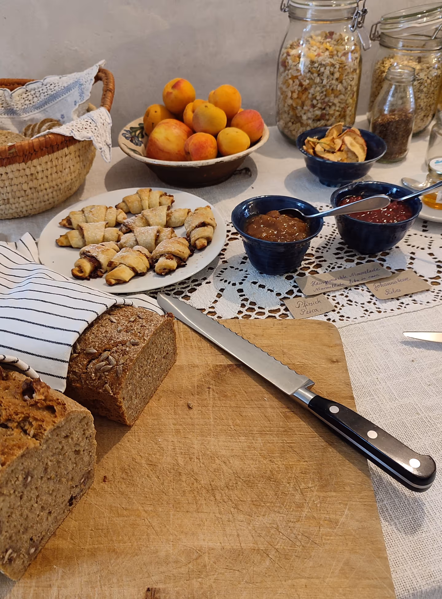 Loaves, nut pastries and homemade preserves with handwritten labels on the breakfast table