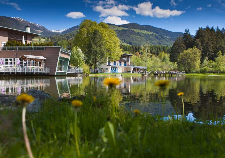 Swimmer leaping from the wooden dock into the green water of the Issinger Weiher, larch forest behind